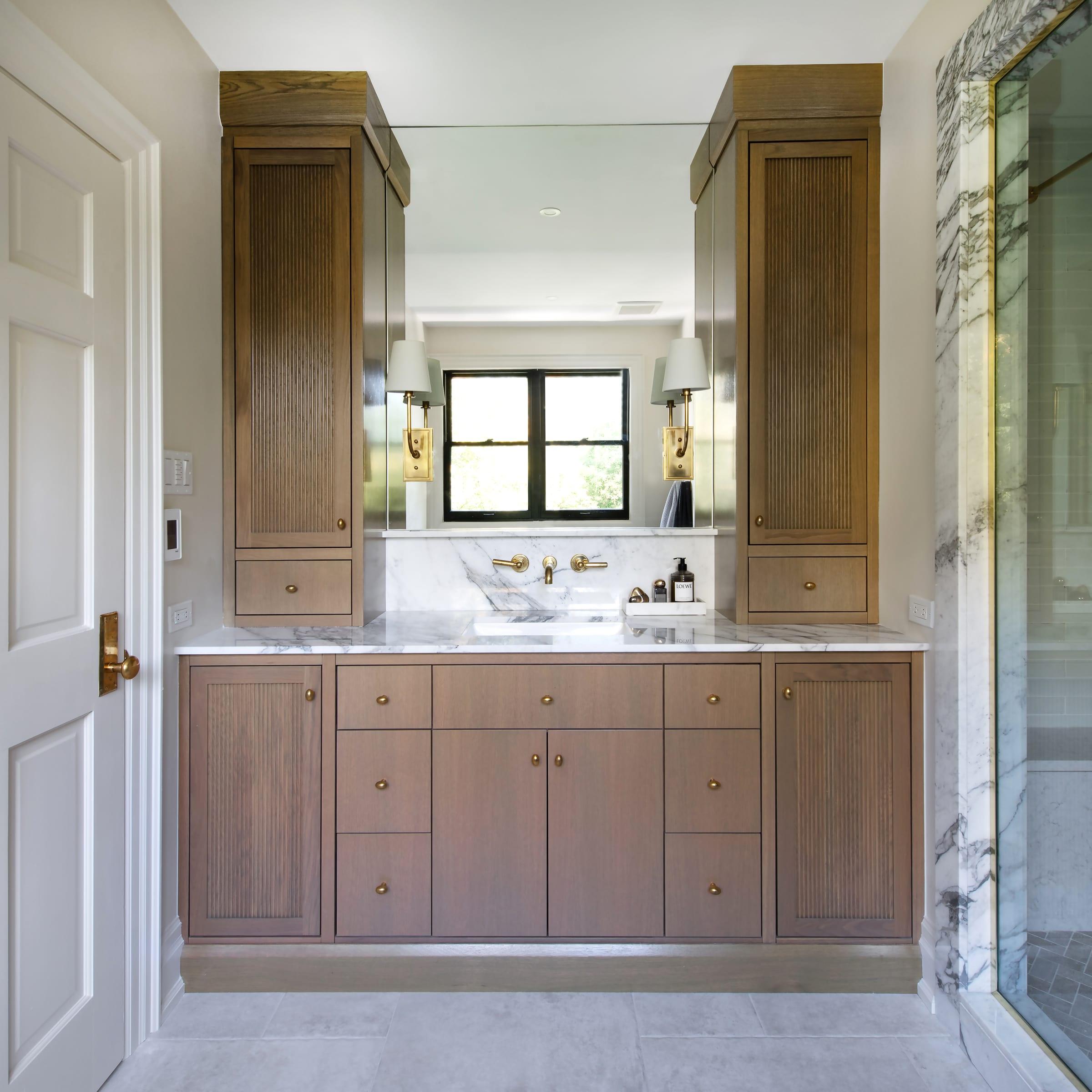 Fitted wood bathroom vanity centred between two tall cabinets