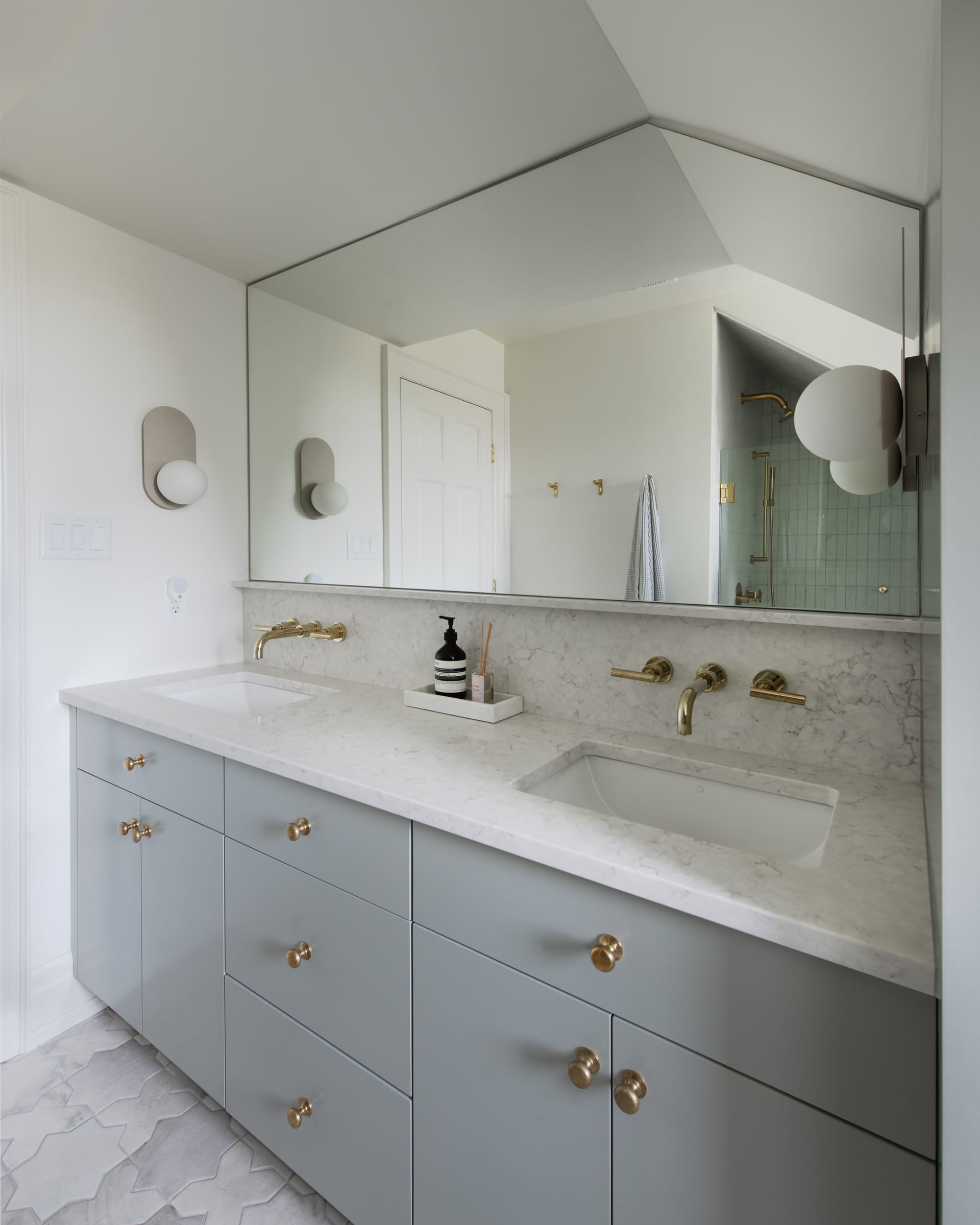 Grey bathroom vanity with brass hardware and wall-mounted fixtures