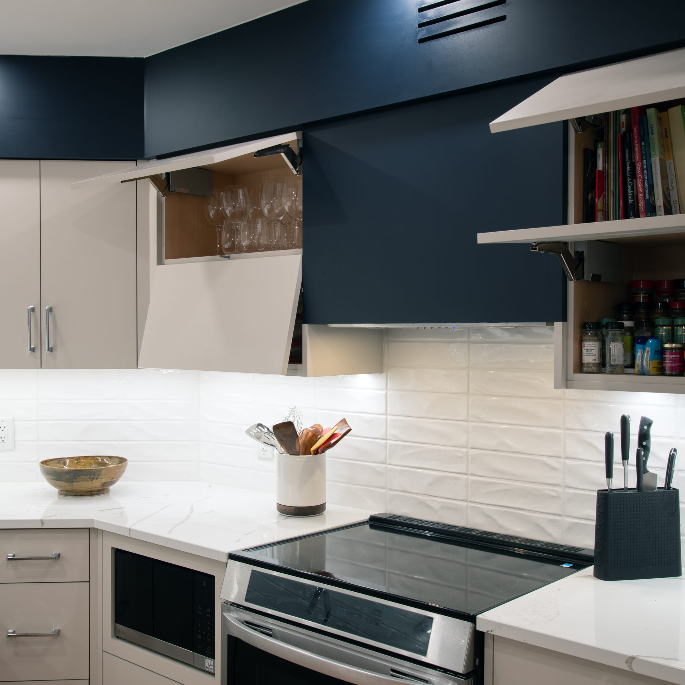 Lift-up cabinets open to reveal glassware, cookbooks, and pantry storage