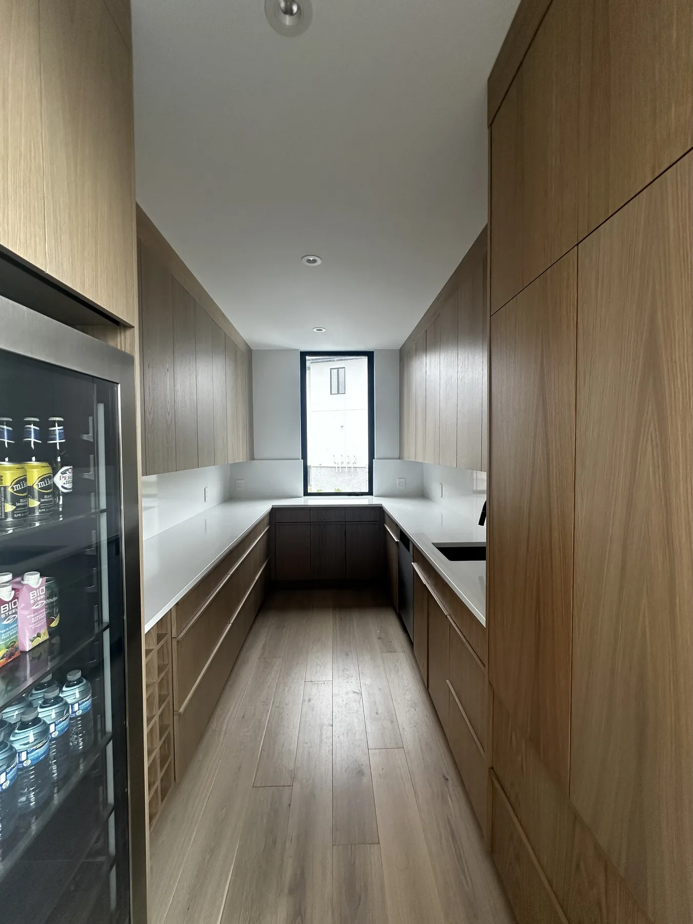 Galley pantry with white oak cabinets and pale counters