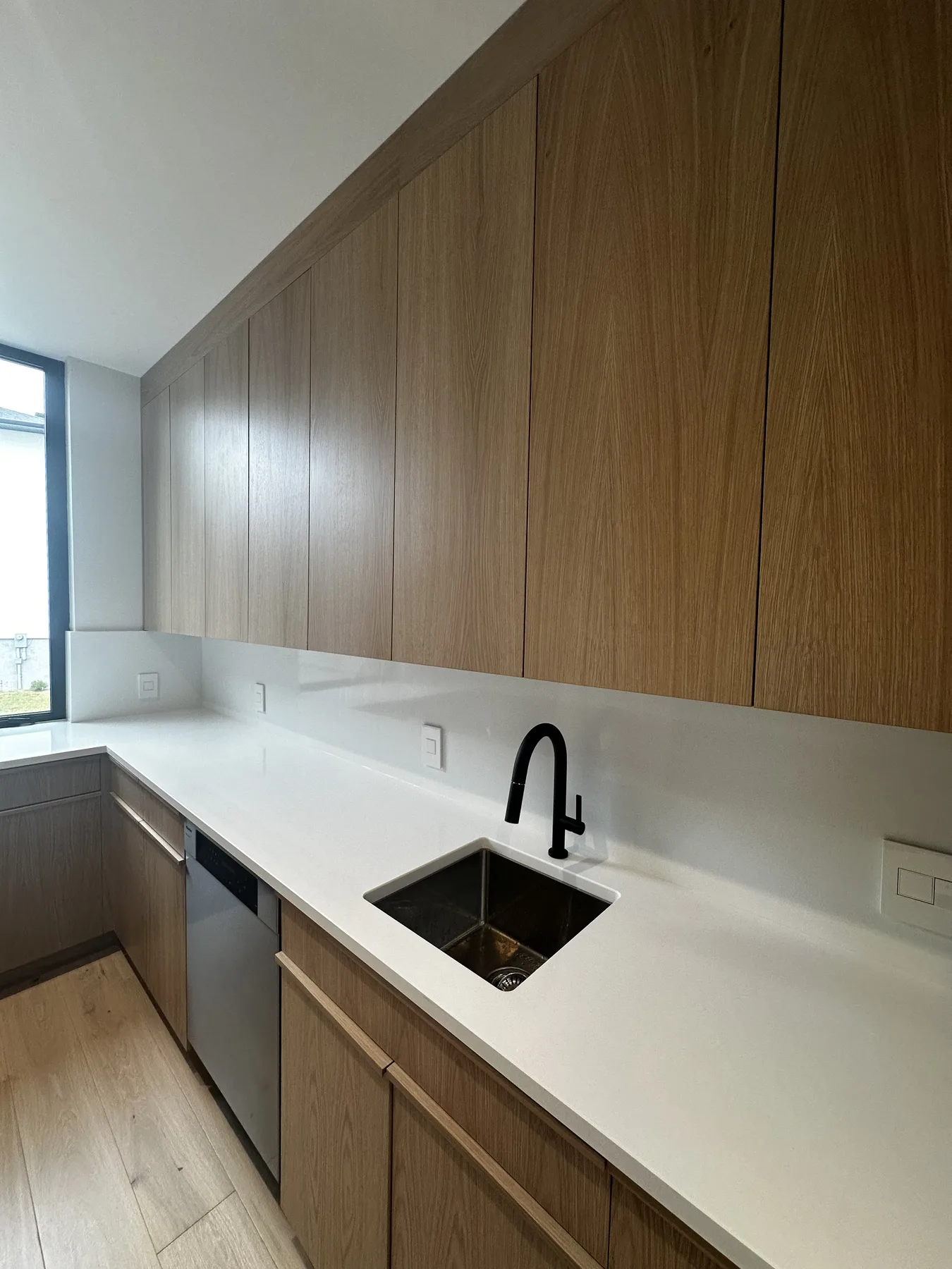 Kitchen sink set beneath white oak upper cabinetry