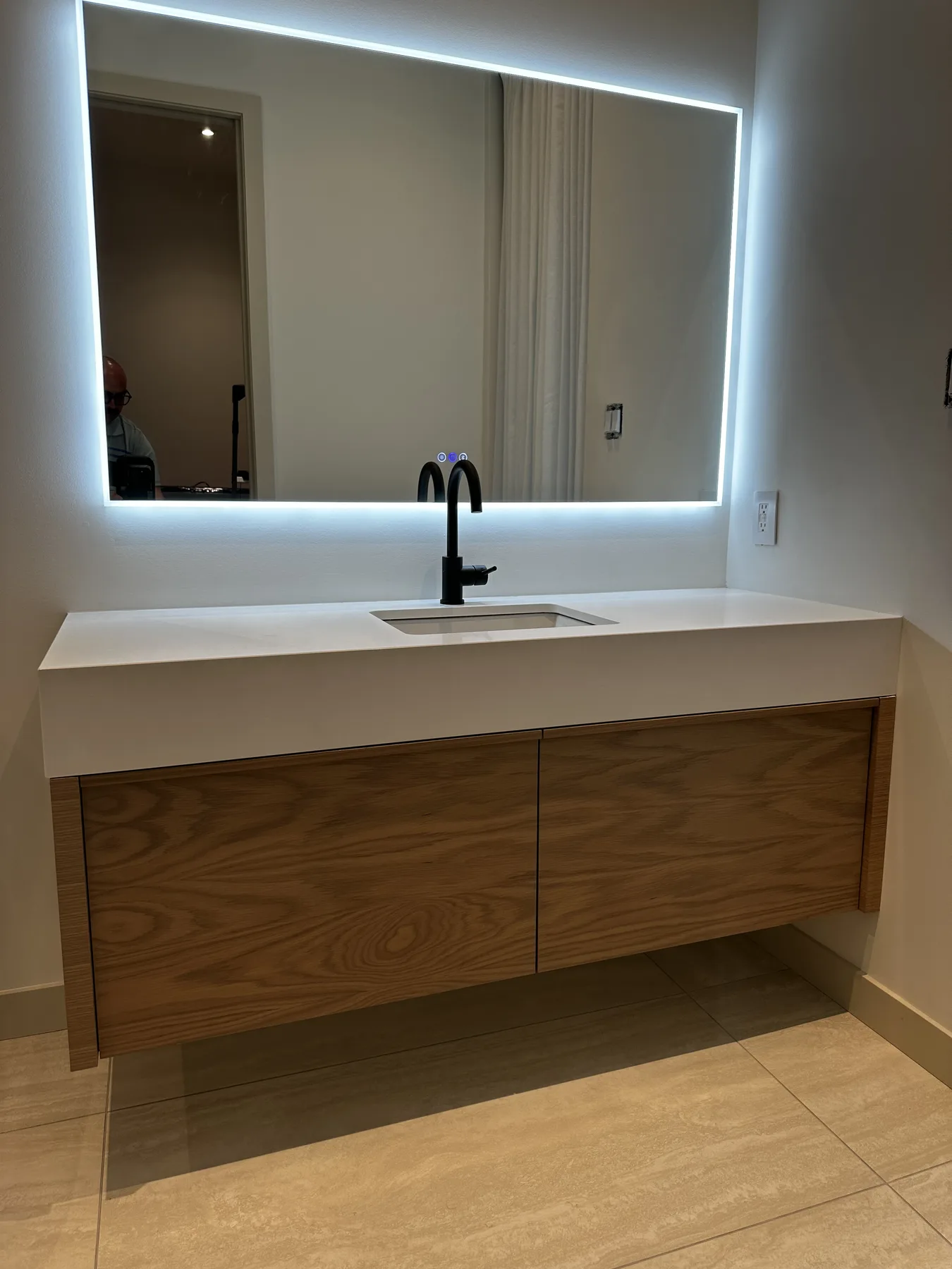 Floating white oak bathroom vanity with illuminated mirror