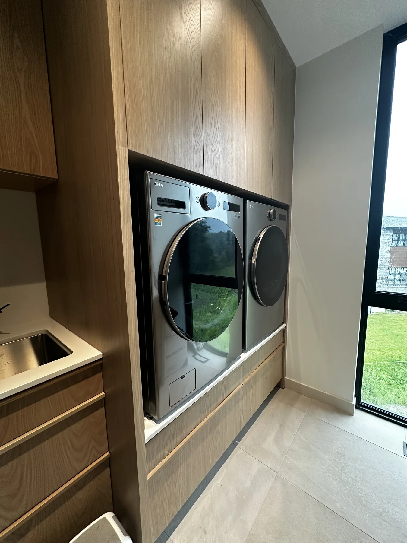 O’Connor laundry with stacked appliances framed by white oak cabinetry