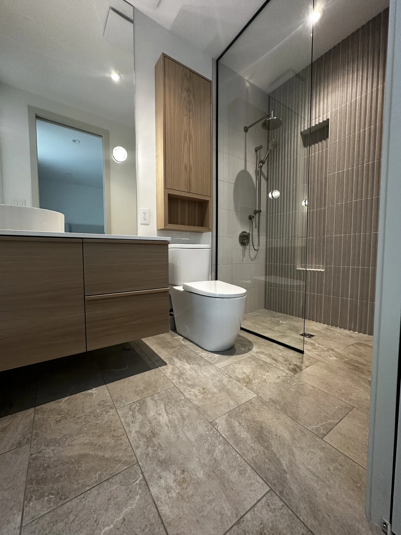 White oak vanity beside a glass shower in the O’Connor Residence
